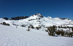 Snow-covered trail to Winnemucca Lake with Round Top in the distance and blue skies overhead