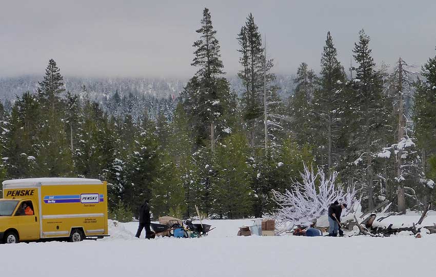 Crew members prepare a filming location in the snowy meadow for a winter scene in Top Gun: Maverick