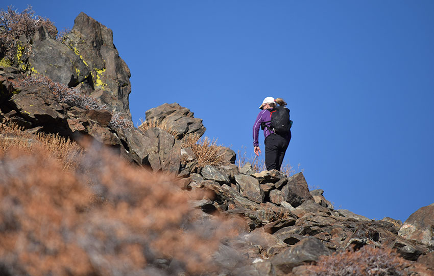 Hiker traveling up a rocky trail with blue skies above