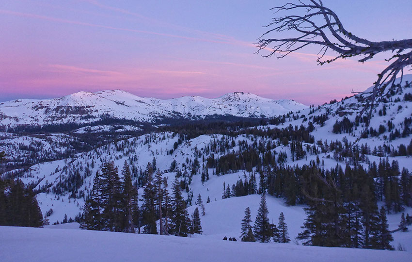 Pastel-colored skies at dusk over a snowy mountain range