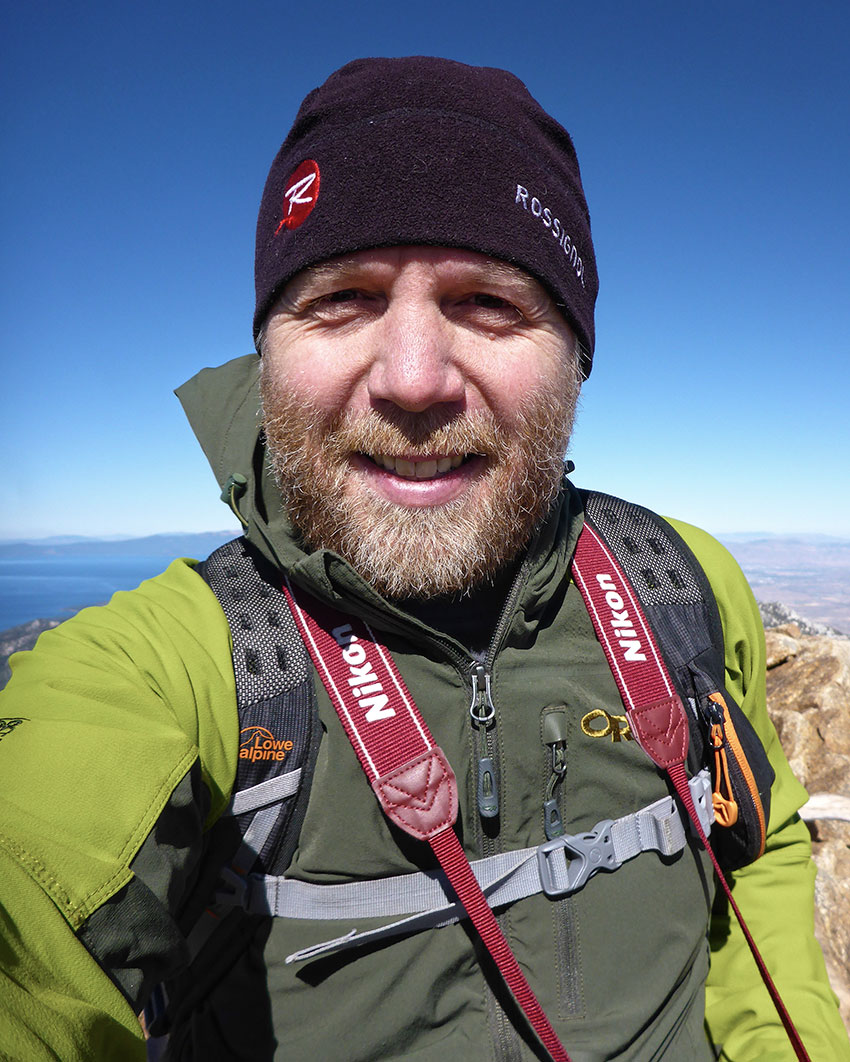 Man on top of mountain with blue skies