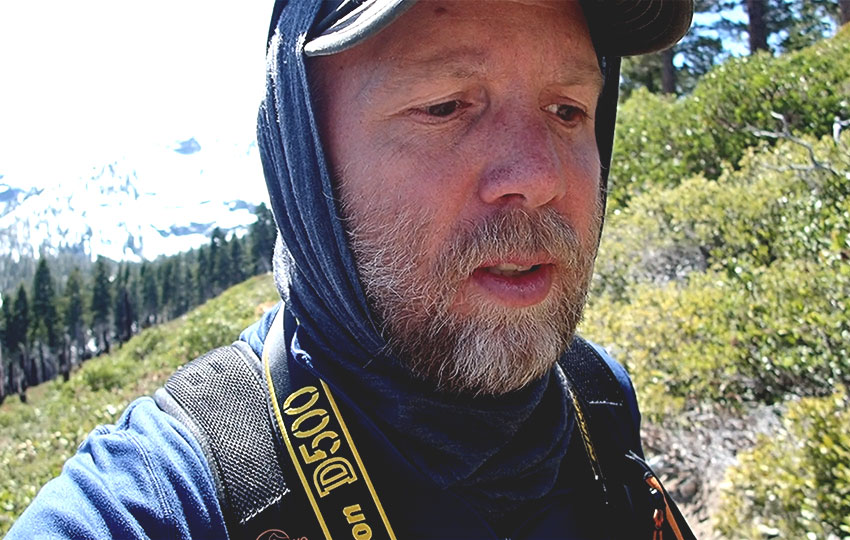 Man hiking in mountains with camera around his neck