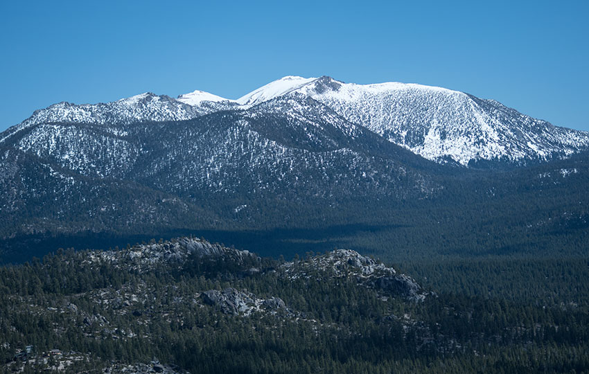 Snow-covered mountains in the distance with blue skies overhead