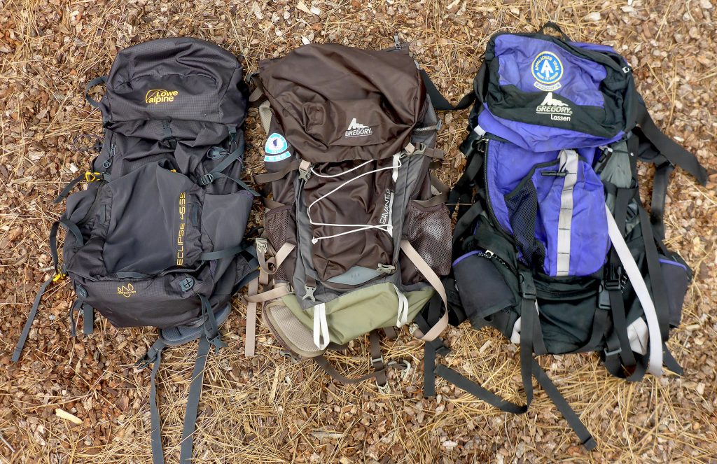 Three different types and sizes of backpacking backpacks on the ground