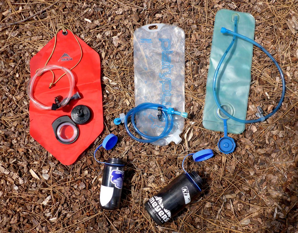 Three different backpacking hydration bladders and two water bottles